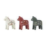 Set of three Siffer resin horse Christmas candle holders in white, red and green, each hand-painted with hearts, snowflakes or folk motifs, shown on a plain white background.