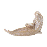 Abitha Shell Stoneware Bowl in beige, a mermaid-shaped dish with a scaled tail forming a shallow bowl and hands cupping a scallop shell, shown on a plain white background.