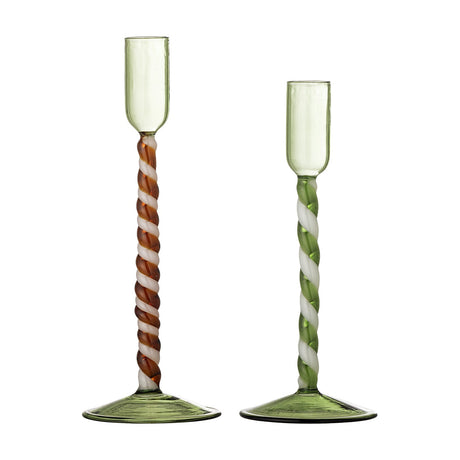 Set of two mouthblown glass candle holders in translucent green with twisted spiral stems in brown-white and green-white, flared round bases, tall narrow cups, on a white background.