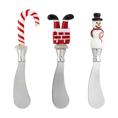 Set of three Misa Christmas butter knives with stainless steel blades and mouthblown glass handles shaped as a candy cane, chimney with Santa's legs, and snowman, on a white background.