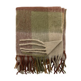 Hamisha Throw in Multi, a folded woven blanket with a muted green, terracotta and beige check pattern and chunky twisted fringe, shown on a plain white background.