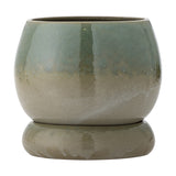 Imke stoneware plant pot with matching saucer, round bulbous body in green reactive glaze fading to beige at the base, shown on a plain white background.