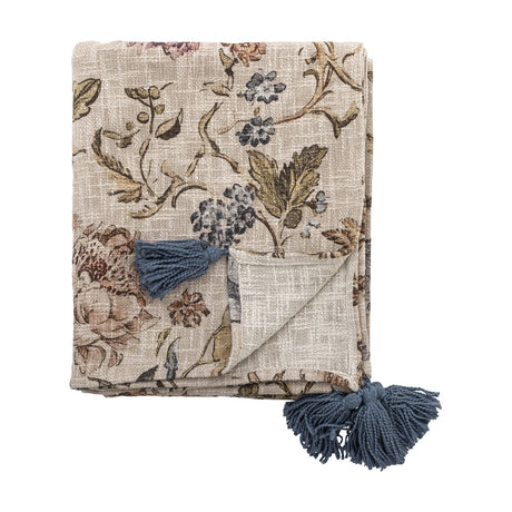 Yoti Floral Cotton Throw in multi, folded showing an all-over floral print in beige, blue and rust tones with blue corner tassels, on a plain white background.