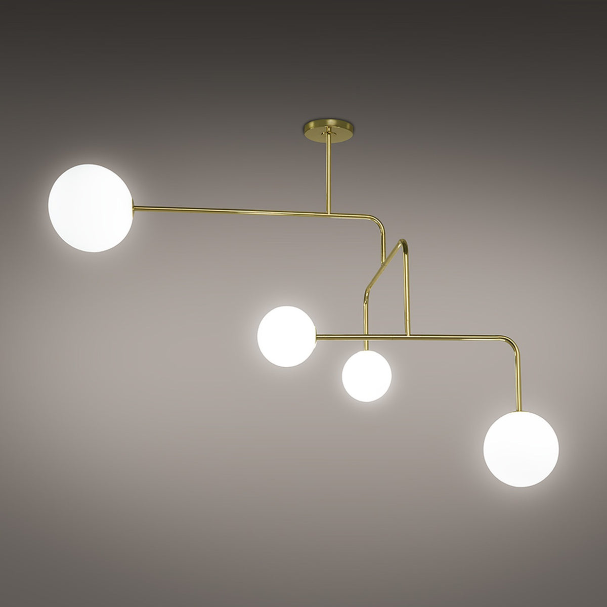 Lumorne 4 Light Glass Globe Chandelier in polished brass, with slanted metal rods at angled bends holding four varied-size opal glass globes, shown against a plain grey background.