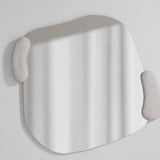 Irregular sculpted wall mirror with two moulded white forms held against its edge, the glass curving between them.