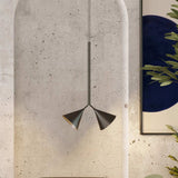Rubi Duo Cone Pendant light with two angled cone shades in matt black with gold interior, hung from a slim rod against a textured concrete archway.