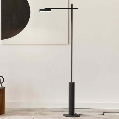 Rafaela LED Disc Floor Lamp in matt black, with a slim iron upright, cylindrical base, and horizontal arm holding a round disc head, shown in a living room setting.