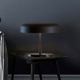 Rea 3 Light Dome Mushroom Table Lamp with wide matt black dome shade and slim stem on a dark marble base, shown on a table in a dark-toned room setting.