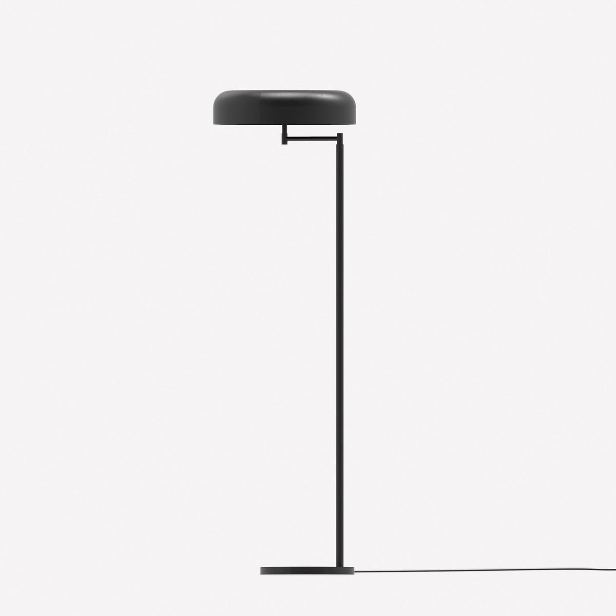 Rea floor lamp in matt black with a shallow dome aluminium shade on an adjustable swing arm, slim iron stem, and round flat base, shown on a plain white background.