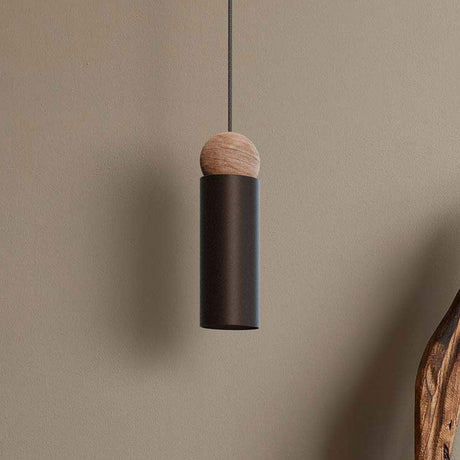 Rocio Wood Pendant Light in matt black, slim cylindrical metal shade topped with a round ash wood ball, hung on a textile cable against a plain neutral wall.