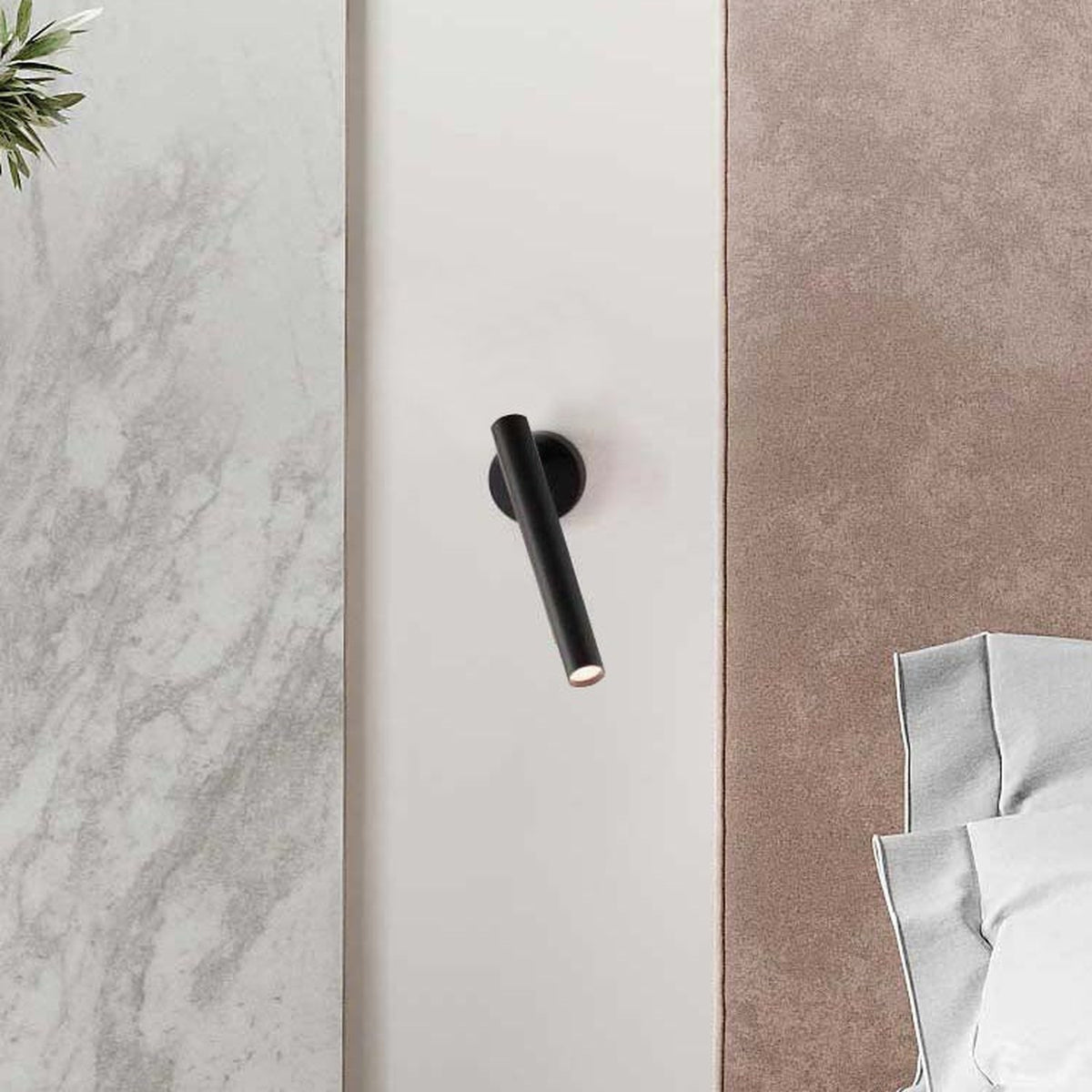 Rui LED adjustable wall light in matt black, slim cylindrical tube on round wall plate, mounted between marble and suede wall panels in a bedroom setting.