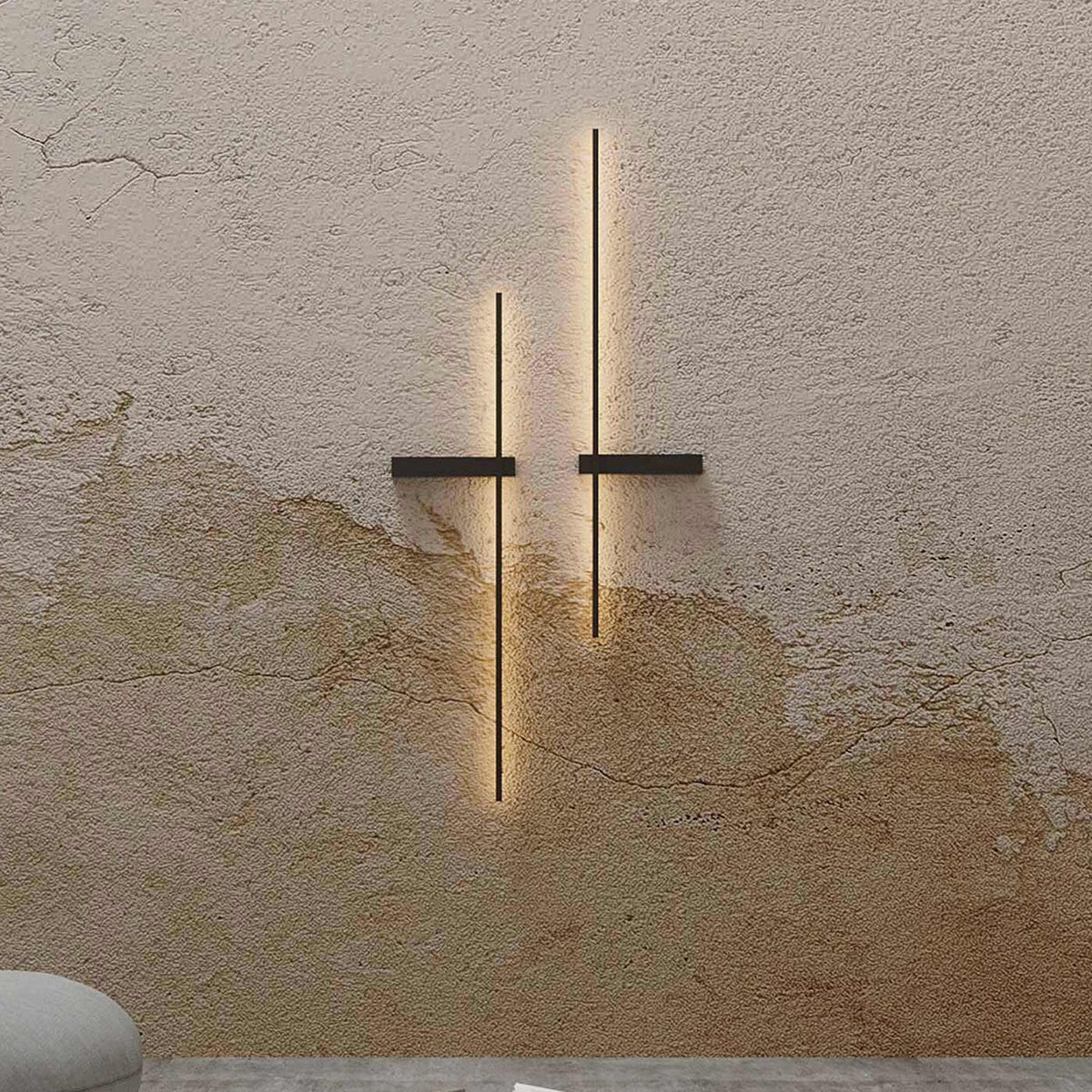 Rut LED Linear Wall Light in matt black, two vertical bars with horizontal mounting brackets, mounted on a textured plaster wall with warm ambient glow.
