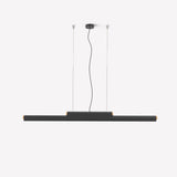 Rudi LED Linear Pendant Light in matt black, a slim iron bar with wood end caps suspended on twin cables from a round ceiling rose, shown on a plain light background.