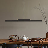 Rudi LED Linear Pendant Light in matt black, a slim iron bar with wood end caps, hung above a wooden dining table set with crockery and a teapot.