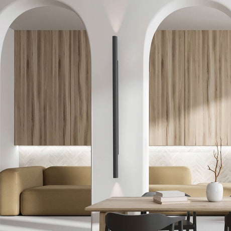Rodi 2 Light Linear Wall Light in matt black iron, mounted between two archways in a living space with wood cabinetry and mustard sofas, casting light up and down the wall.