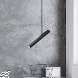 Rhoda Adjustable Linear Pendant Light in matt black iron, slim angled tube shade with GU10 lamp, hung against a grey textured wall above a wire basket.