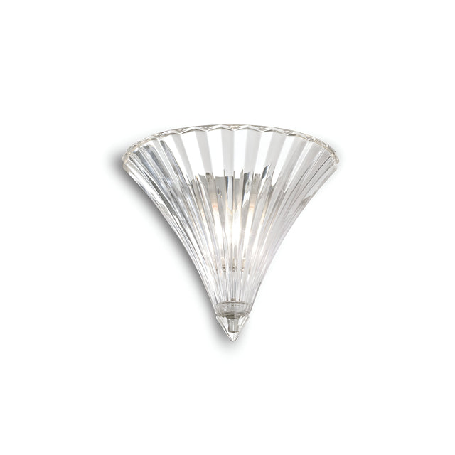 The Spring Small Glass Wall Light - Clear is a wall-mounted fixture featuring chromed metal accents and a conical design. Its clear, fluted glass gracefully fans out from a narrow base to a wide top, creating a stunning piece that emits a soft, ambient glow.