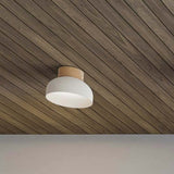 Reiko Dome Flush Ceiling Light mounted on a wood-panelled ceiling, showing its matt white aluminium dome shade and natural ash wood base, single E27 fitting.