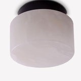 Rock LED Alabaster Drum Flush Ceiling Light in Black, showing a cylindrical alabaster shade on a black aluminium base against a plain white background.