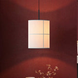 Rania cylinder pendant light with white cream fabric shade and fine grid seams, hung from a matt black iron fitting against a dark red wall.