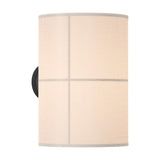 Rania cylinder fabric wall light with white cream shade divided into four panels by fine lines, mounted on a round black base, shown on a plain white background.