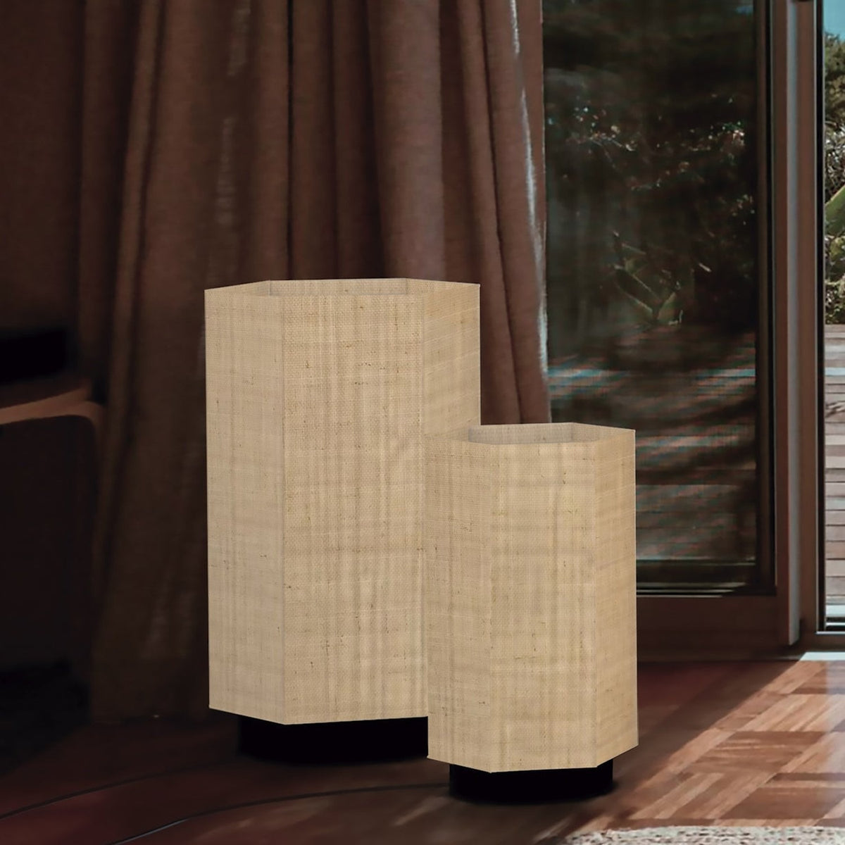 Roxi Fabric Floor Lamp in natural fibre with hexagonal shade and dark round base, shown in two sizes beside a curtained window in a living room.