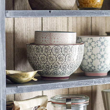 Cécile ceramic bowl 13.5cm with floral circle pattern in grey on cream, shown on a wooden shelf alongside a pink patterned bowl and scalloped bowl.