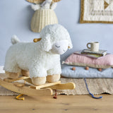 Laasrith Rocking Sheep in white, a curly fabric ride-on toy with sleepy embroidered face, wooden side handles and curved rockers, shown in a nursery setting with cushions and books.