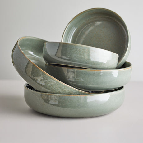 Stack of Pixie Stoneware Bowls, 20cm, in glossy green with a speckled reactive glaze, shown in varying shapes against a plain light background.