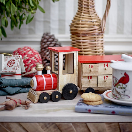 Grunk Wooden Advent Calendar in natural paulownia, styled as a toy train with locomotive and drawer carriages numbered 14 to 17, shown among festive décor.
