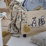 Filipa Floral Cotton Throw in multicoloured fern and leaf print with mustard tassel corners, draped over a toy storage box in a nursery setting.