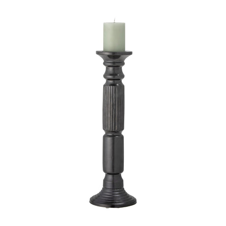 Millas Fluted Ceramic Candle Holder in black, a tall pillar-shaped column with a textured fluted midsection, shown with a pale green pillar candle on a white background.