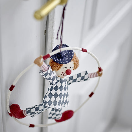 Alfredo Cotton Baby Mobile in Multi, a fabric clown figure in harlequin print and polka-dot cap set within a padded hoop, hanging from a white door handle.