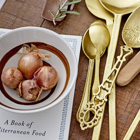 Heikki Floral Stoneware Bowl, 12cm, with brown rim and shallots inside, shown on a rustic wooden table beside gold cutlery and a cookbook.
