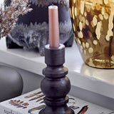 Hui Stoneware Candle Holder in black with a turned profile, slim socket, stacked rings and rounded centre, holding a pink taper candle on a shelf.