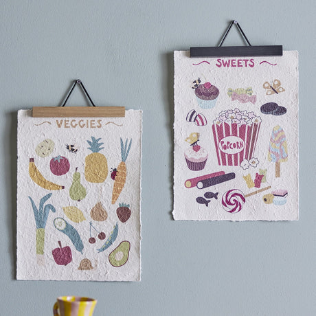 Papio Posters Set of 2 in Multi, wood-clipped SWEETS and VEGGIES wall art prints with colourful food illustrations, hung on a light grey wall.