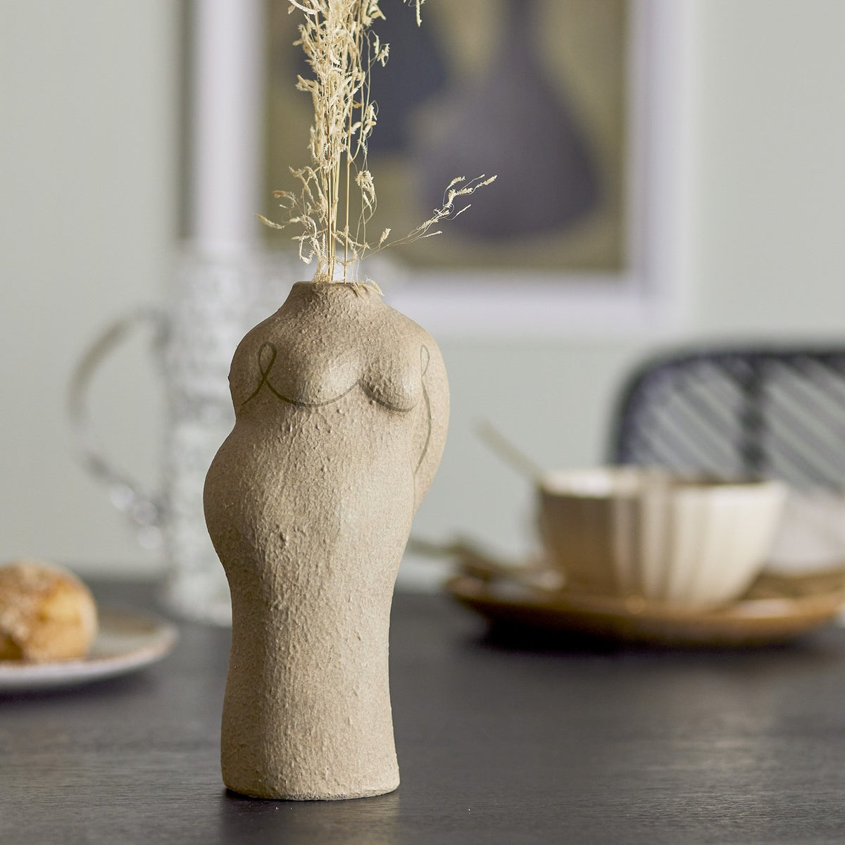 Lulu Terracotta Vase 19.5cm in beige, shaped like a woman's torso with a textured sandstone-like finish, styled on a table holding dried grasses.
