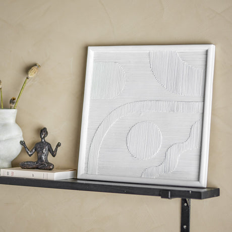 Patina Resin Wall Decor in white, a square ridged relief panel with arch and circle motifs, shown on a shelf beside a ceramic vase and small sculpture.