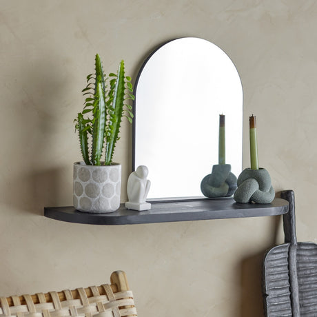 Annlie Wall Mirror with Shelf 72x48cm in black, arched mirror on a black MDF shelf with rounded ends, styled with a potted plant, figurine and candle holders.