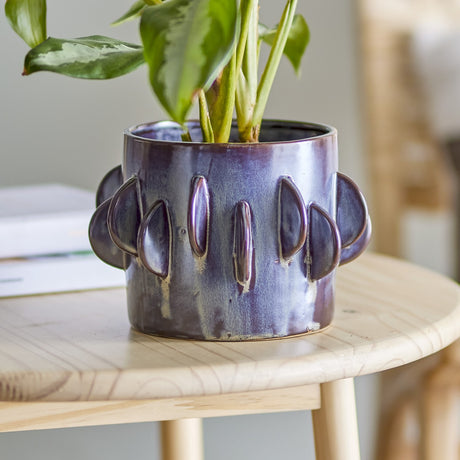 Roza Stoneware Plant Pot in grey, round ceramic planter with raised half-moon fins around the upper body, holding a leafy plant on a wooden side table.