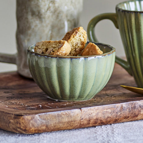 Latina Stoneware Bowl 12cm in green, fluted sides and wavy rim, filled with biscuits on a wooden board beside matching mugs.