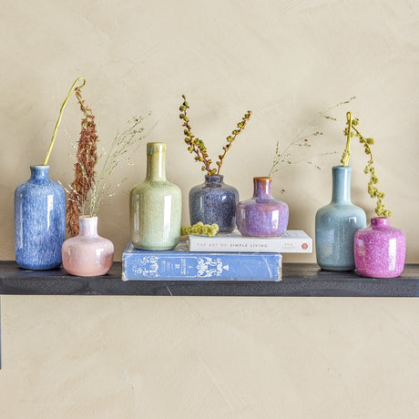 Maien Speckled Stoneware Vases, 14cm set of 7 in blue, green, pink and purple speckled glaze, varied bottle and rounded shapes with dried stems, on a dark shelf with books.