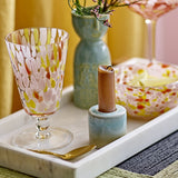 Lilya Speckled Wine Glass in pink with a flared bowl, short stemmed foot, styled on a marble tray beside a teal vase, candle holder and matching speckled bowl.