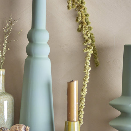 Isolde Stoneware Vase 28.5cm in matt green, with a cone-shaped base rising into rounded rings and a slim neck, displayed indoors beside a candle and dried foliage.