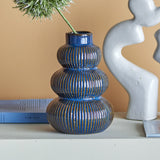 Myrtle Striped Stoneware Vase 20cm in blue, three ribbed rounded tiers with a short neck, shown on a shelf beside books and a grey sculptural ornament.