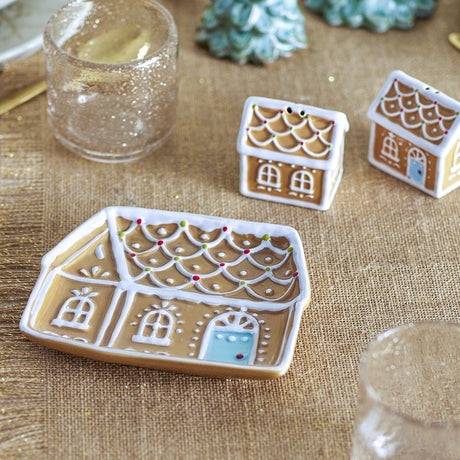 Ginnie Gingerbread House ceramic Christmas platter in brown, shaped like a house with pitched roof, arched windows and blue door, styled with small gingerbread house ornaments and glassware.