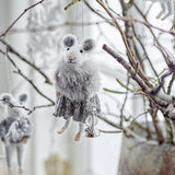 Peo Wool Christmas Tree Decoration mouse figure in grey, with a fluffy stole and knitted skirt, holding a small bell, hanging among bare branches.