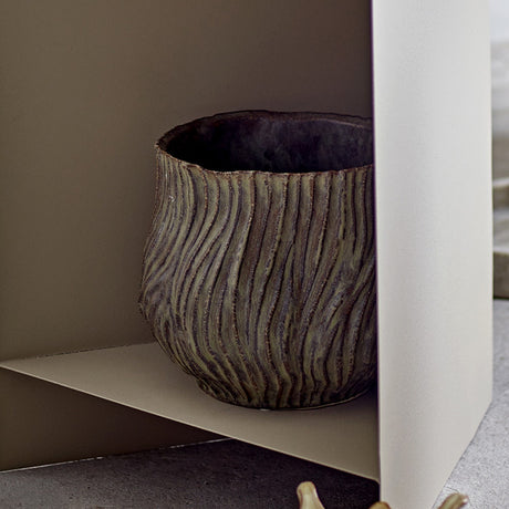 Dua Stoneware Plant Pot in brown, a rounded ceramic planter with rippled, ridged texture and a rough-notched rim, shown on a shelf in a neutral-toned interior.