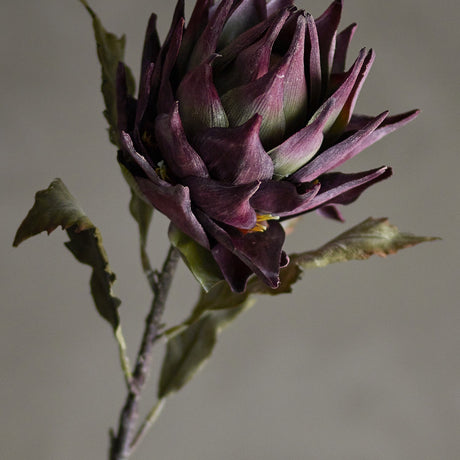 Artificial protea stem in purple, 76cm tall, showing a dense layered flower head with pointed petals on a slender stem with wavy-edged leaves, set against a neutral background.