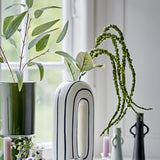 Foxtail Artificial Stem in green, trailing beaded tassels and broad leaves arching above ceramic vases on a windowsill.